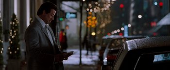 Movie still from “Get Carter” (2000), directed by Stephen Kay – A man standing on the side of the street looking at his cell phone; Medium shot, Over the shoulder angle