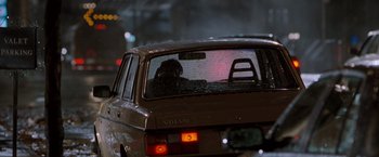 Movie still from “Get Carter” (2000), directed by Stephen Kay – A person sitting in the passenger seat of a car on a street; Wide shot, Over the shoulder angle