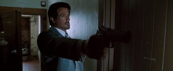 Movie still from “Get Carter” (2000), directed by Stephen Kay – A man holding a gun in a room; Close Up shot, Low angle