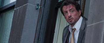 Movie still from “Get Carter” (2000), directed by Stephen Kay – A man wearing a suit and tie standing in front of a window; Close Up shot, Low angle