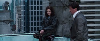 Movie still from “Get Carter” (2000), directed by Stephen Kay – A woman sitting on the side of a building; Wide shot, Over the shoulder angle