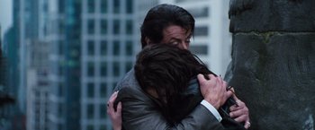 Movie still from “Get Carter” (2000), directed by Stephen Kay – A man hugging a woman in front of a tall building; Close Up shot, Low angle
