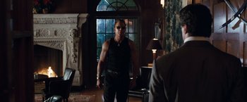 Movie still from “Get Carter” (2000), directed by Stephen Kay – A man in black shirt and sunglasses in a living room; Medium shot, Over the shoulder angle