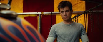 Movie still from “Ghost Rider” (2007), directed by Mark Steven Johnson – A man in a grey t - shirt is standing in front of a yellow wall; Close Up shot, Over the shoulder angle