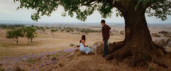 Movie still from “Ghost Rider” (2007), directed by Mark Steven Johnson – A man and a woman sitting on top of a rock in a field; Wide shot, High angle