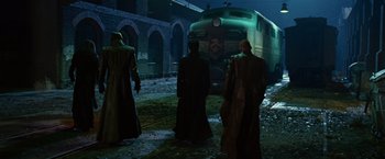Movie still from “Ghost Rider” (2007), directed by Mark Steven Johnson – A group of men standing in front of a train at night; Wide shot, Low angle