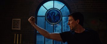 Movie still from “Ghost Rider” (2007), directed by Mark Steven Johnson – A man holding his fist up in front of a stained glass window; Medium shot, Low angle