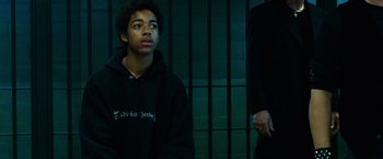 Movie still from “Ghost Rider” (2007), directed by Mark Steven Johnson – A young man in a black hoodie looks up at a wall; Medium shot, Over the shoulder angle