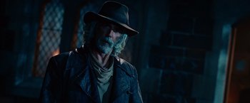 Movie still from “Ghost Rider” (2007), directed by Mark Steven Johnson – An old man with a beard and a hat is smoking a cigarette; Close Up shot, Over the shoulder angle