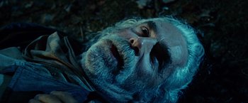 Movie still from “Ghost Rider” (2007), directed by Mark Steven Johnson – An old man with a long beard laying on the ground; Close Up shot, Overhead angle