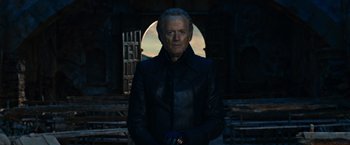 Movie still from “Ghost Rider” (2007), directed by Mark Steven Johnson – An older man in a leather jacket standing in front of an archway; Medium shot, Low angle