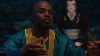 Movie still from “Ghost in the Shell” (2017), directed by Rupert Sanders – A man in a blue and yellow outfit talking to someone; Close Up shot, Over the shoulder angle