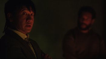 Movie still from “Ghost in the Shell” (2017), directed by Rupert Sanders – A man standing in a dark room next to another man; Close Up shot, Over the shoulder angle