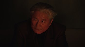 Movie still from “Ghost in the Shell” (2017), directed by Rupert Sanders – An older man with a gray hair and a black suit; Close Up shot, Over the shoulder angle