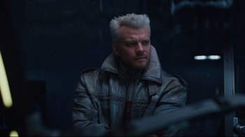 Movie still from “Ghost in the Shell” (2017), directed by Rupert Sanders – A man with white hair is sitting in a dark room; Close Up shot, Low angle