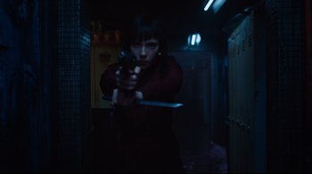 Movie still from “Ghost in the Shell” (2017), directed by Rupert Sanders – A woman holding a gun in a dark room; Medium shot, Low angle
