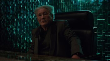 Movie still from “Ghost in the Shell” (2017), directed by Rupert Sanders – An older man sitting at a table in front of a wall of lights; Medium shot, Low angle