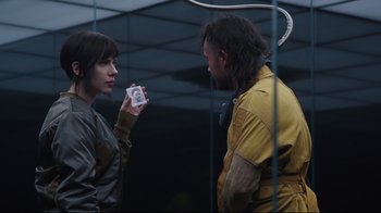 Movie still from “Ghost in the Shell” (2017), directed by Rupert Sanders – A man and a woman are holding something in their hands; Close Up shot, Over the shoulder angle