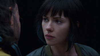 Movie still from “Ghost in the Shell” (2017), directed by Rupert Sanders – A person with short black hair; Close Up shot, Over the shoulder angle