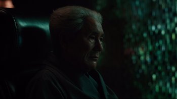 Movie still from “Ghost in the Shell” (2017), directed by Rupert Sanders – An older man sitting in a chair in the dark; Close Up shot, Over the shoulder angle