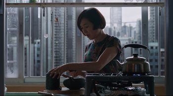 Movie still from “Ghost in the Shell” (2017), directed by Rupert Sanders – A woman in a green dress is making a cup; Medium shot, Low angle