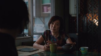Movie still from “Ghost in the Shell” (2017), directed by Rupert Sanders – A woman sitting at a table with a cup of tea; Medium shot, Over the shoulder angle