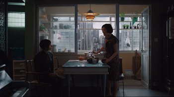 Movie still from “Ghost in the Shell” (2017), directed by Rupert Sanders – A woman standing at a table with a bowl of food; Wide shot, Over the shoulder angle