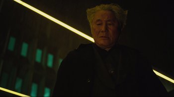 Movie still from “Ghost in the Shell” (2017), directed by Rupert Sanders – An older man with blonde hair is standing in the dark; Close Up shot, Low angle