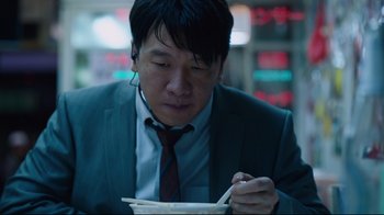 Movie still from “Ghost in the Shell” (2017), directed by Rupert Sanders – A man sitting at a table with chopsticks in his hands; Close Up shot, High angle