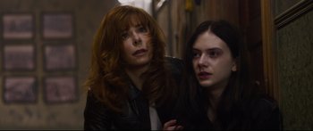 Two women are posing for a picture in a dark alley