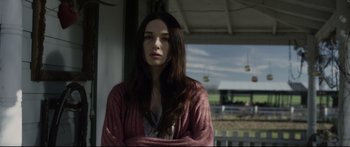 A woman with long brown hair standing on a porch