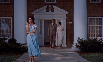 Movie still from “Giant” (1956), directed by George Stevens – Two women and a man are walking in front of a building; Wide shot, Low angle