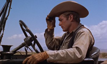 Movie still from “Giant” (1956), directed by George Stevens – A man in a cowboy hat sitting at the steering wheel of a truck; Close Up shot, Low angle