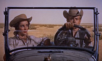 Movie still from “Giant” (1956), directed by George Stevens – A man and a woman driving a car in a field; Medium shot, Low angle