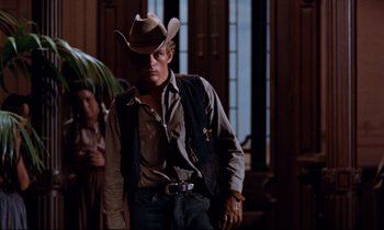Movie still from “Giant” (1956), directed by George Stevens – A man wearing a cowboy hat standing next to a woman; Medium shot, Low angle