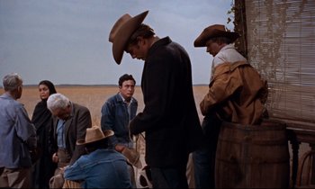 Movie still from “Giant” (1956), directed by George Stevens – A group of men standing next to each other on a field; Medium shot, Over the shoulder angle