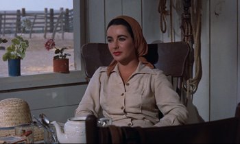Movie still from “Giant” (1956), directed by George Stevens – A woman sitting in a chair wearing a head scarf; Medium shot, Over the shoulder angle