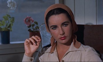 Movie still from “Giant” (1956), directed by George Stevens – A person sitting in a chair wearing a headscarf; Close Up shot, High angle