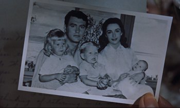 Movie still from “Giant” (1956), directed by George Stevens – An old photo of a family holding a baby; Close Up shot, Overhead angle