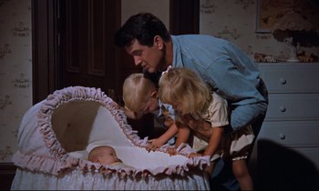 Movie still from “Giant” (1956), directed by George Stevens – A man and two children looking at a baby in a bassinet; Medium shot, High angle