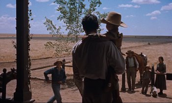Movie still from “Giant” (1956), directed by George Stevens – A group of men standing on top of a dirt field; Wide shot, Low angle