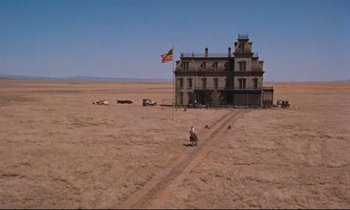 Movie still from “Giant” (1956), directed by George Stevens – An american flag flies in front of an abandoned house; Extreme Wide shot, Low angle