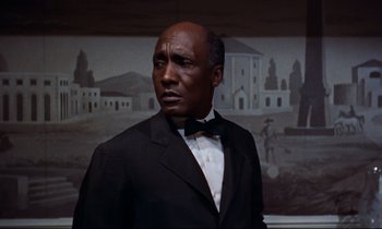Movie still from “Giant” (1956), directed by George Stevens – A man in a tuxedo standing in front of a painting; Close Up shot, Low angle