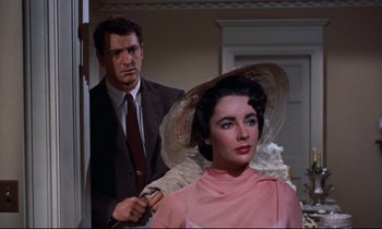 Movie still from “Giant” (1956), directed by George Stevens – A man and a woman are standing in front of a door; Medium shot, Over the shoulder angle