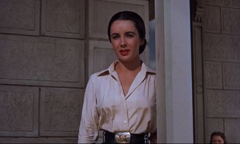 Movie still from “Giant” (1956), directed by George Stevens – A woman standing in front of a door wearing a white shirt; Medium shot, Low angle