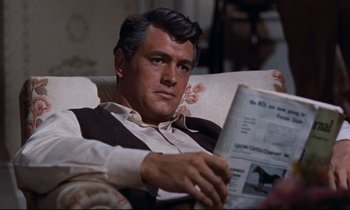 Movie still from “Giant” (1956), directed by George Stevens – A man sitting in a chair holding a newspaper; Close Up shot, High angle