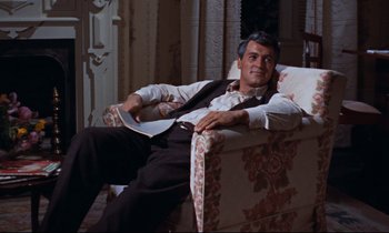 Movie still from “Giant” (1956), directed by George Stevens – A man sitting in a chair in a room; Medium shot, High angle