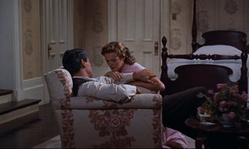 Movie still from “Giant” (1956), directed by George Stevens – A man and a woman sitting on a couch; Medium shot, High angle
