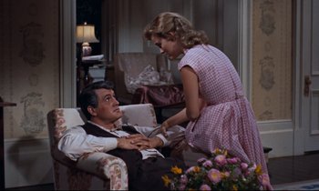 Movie still from “Giant” (1956), directed by George Stevens – A man and a woman sitting on a couch; Medium shot, High angle