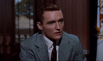 Movie still from “Giant” (1956), directed by George Stevens – A man wearing a suit and tie sitting in a room; Close Up shot, High angle